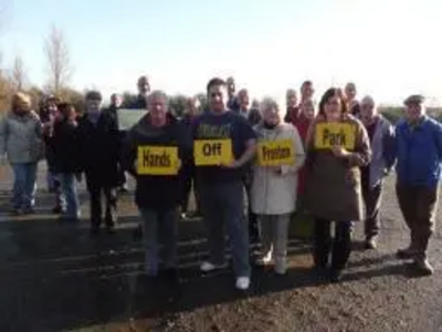 Group of Protestors in Preston Park holding Hands Off Preston Park placards